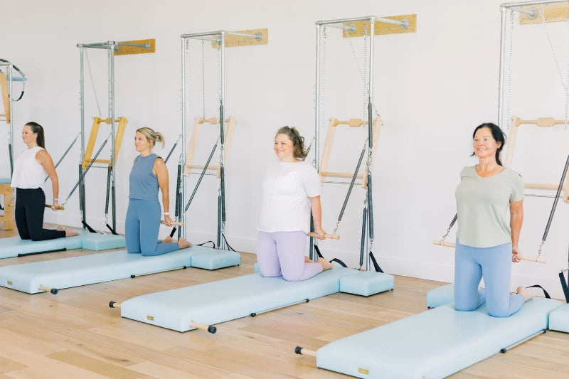 Clients exercising on Studio Wall unit with High Mat using the Roll Down Bar